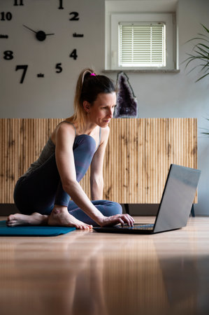 Young woman sitting on a living room floor using laptop computer to study or work. Freelance work and working from home conceptual image.の写真素材