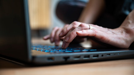 Low angle closeup view of female hands using laptop computer typing on keypad.