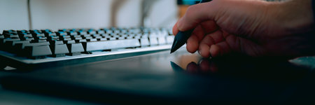 Closeup view of a designer or illustrator using a digital stylus pen working on a tablet. Wide view image.の写真素材