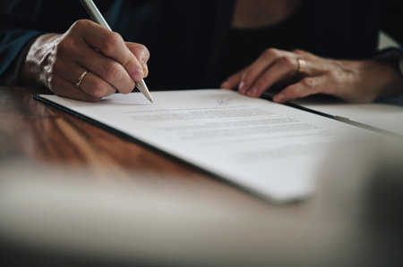 Low angle closeup view of businesswoman signing a document or contract.の写真素材