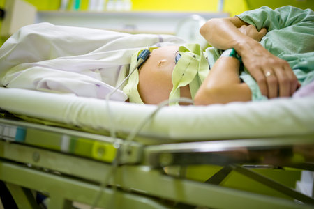 Low angle view of a pregnant woman lying in a hospital bed with baby heart rate monitor attached to her big swallen belly.の写真素材