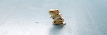 Stack of Euro coins placed over textured blue wooden background. Wide view image with copy space.の写真素材