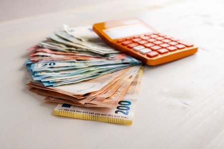 Pile of various value Euro banknotes money spread on the table with an orange calculator on the cash. Conceptual image of savings, budget and costs.の写真素材
