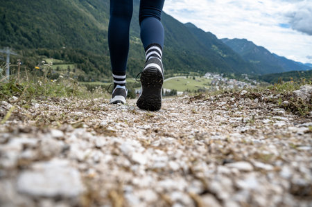 Low angle closeup view of female legs in hiking shoes walking on a trail in beautiful mountains.の写真素材