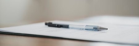 Low angle view of a black pen lying on a paperwork, contract or legal documets. Wide view image.の写真素材