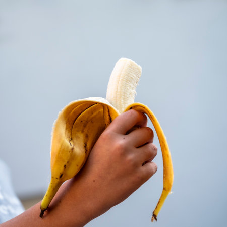 Closeup view of hand of a child holding a half eaten banana in a peel. With copy space.の写真素材