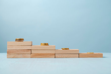 Conceptual image of financial growth and success. Steps made of wooden pegs with stack of coins on...