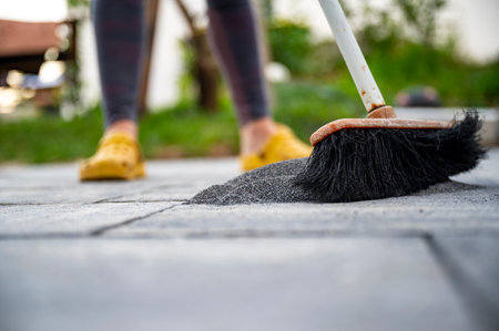 Low angle view of a person brushing filling sand into the gaps between newly layed concrete tiles in a do it yourself construction project of paving domestic patio.の写真素材
