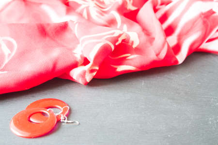 Red earrings and red scarf close-up on stone backgroundの写真素材