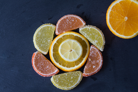 Colorful sugary marmalade like lemon and orange slices covered with sugar. Fruit jelly candies. Dolce vita. Closeup. Top view  on slate.の写真素材