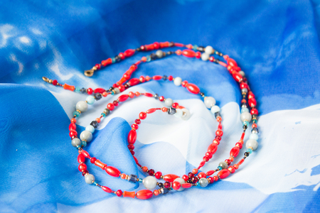 blue and red beads on a background of blue silkの写真素材