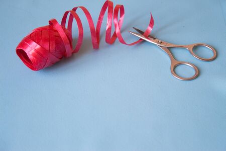 Scissors cut the red ribbon on blue backgroundの写真素材