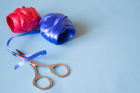 Blue ribbon and red ribbon scissors cut the blue ribbon on blue backgroundの写真素材