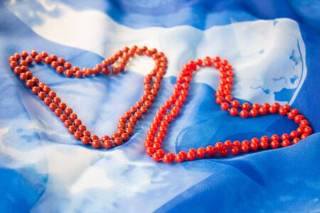Two hearts of beads on a background of blue silkの写真素材