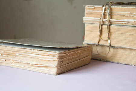 stack of old books with a necklace pink backgroundの写真素材