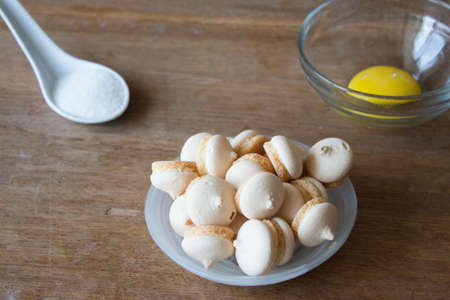 Close up of cookies in decorative dish with sugar and egg . Wooden board.の写真素材