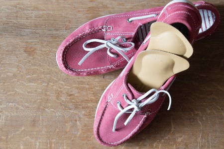 Pink sport shoes  with orthopedic insoles.  Pair of sneakers on wooden background