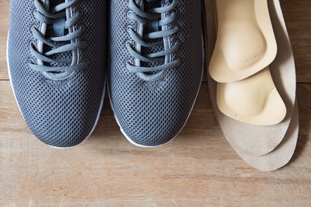 Gray sport shoes with orthopedic insoles. Wooden background.の写真素材