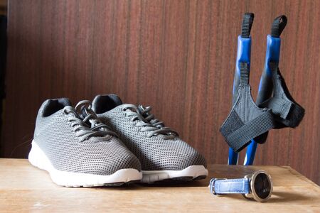 Gray sport shoes  with Nordic Walking sticks and chronometer.  Pair of sneakers on wooden backgroundの写真素材