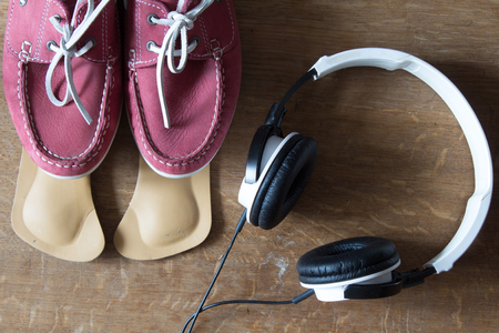 Pink sport shoes  with orthopedic insoles and  headphones.  Pair of sneakers on wooden backgroundの写真素材