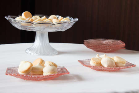 Vase with cookies on a round table. Pink shallow decorative dish with biscuits.の写真素材