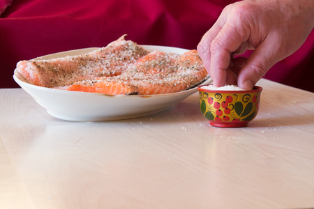 Salting raw salmon fish with  lemon, pepper, sea salt.の写真素材