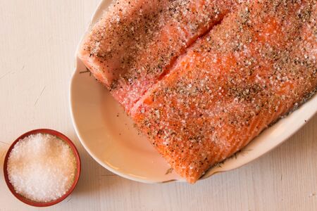 Salting raw salmon fish with  lemon, pepper, sea salt. Top view.の写真素材