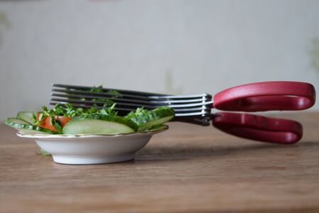 Special herb scissors with multiple blades. Green parsley cut into special scissors. wooden board