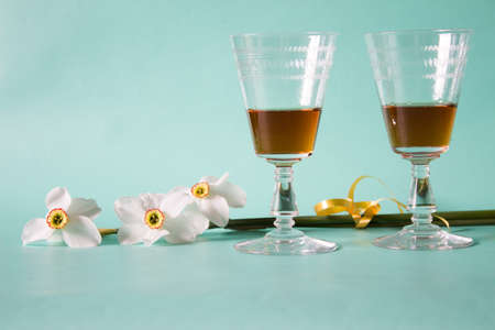 Two glasses of cognac or brandy and white daffodils on a neutral background, Romantic gift.の写真素材