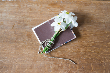 White daffodils bouquet on wooden background. Narcissus flowers and notebook. Romantic gift.の写真素材