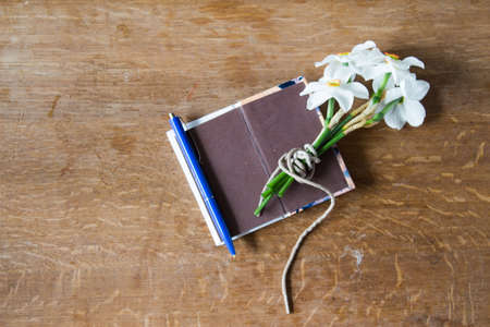 White daffodils bouquet on wooden background. Narcissus flowers and notebook. Romantic gift.