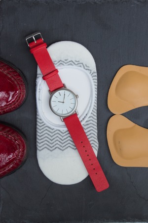 Leather orthopedic insoles, socks, wrist watch and red shoes on stone background. Top view.の写真素材