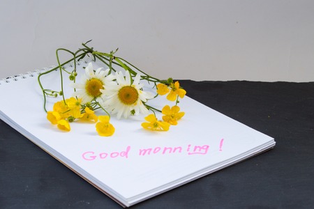 Bouquet of flowers buttercups and chamomiles and notes good morning on stone. Top view.の写真素材