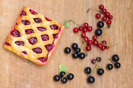 The cake with berry jam and red and black currants on wooden table. Top view.の写真素材