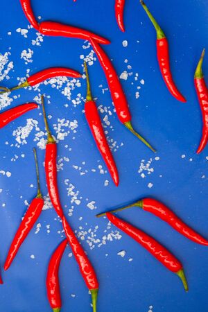 Hot chili pepper and sea salt on blue background. Top view.の写真素材