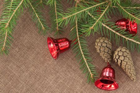 Corner made of green spruce branches with red bells and fir cones. Top view.の写真素材