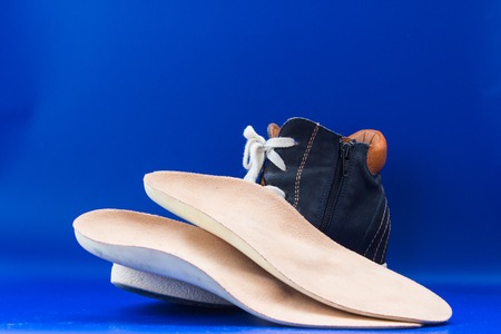 Leather orthopedic insoles with boot. Blue background.の写真素材