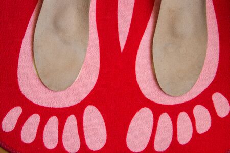 Leather orthopedic insoles are located on a red home carpet with the image of the feetの写真素材