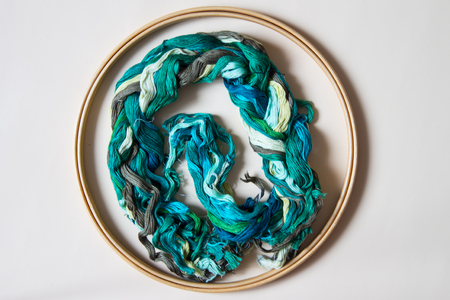 Hoop with threads of green tones for embroidery. Top view. Beige background.の写真素材