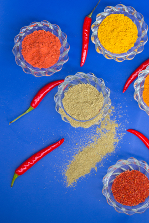 Colorful spices and herbs in glass dishes on a blue background. Top view.の写真素材