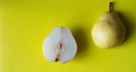 Yellow fresh pear cut in half on yellow background. Top view.の写真素材