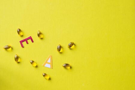 Gel capsules with vitamins A and E on yellow background. Top view.の写真素材