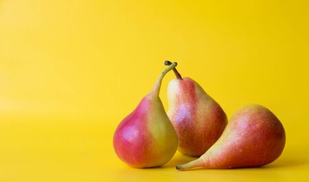 Three red yellow fresh pears isolated on  yellow background.の写真素材
