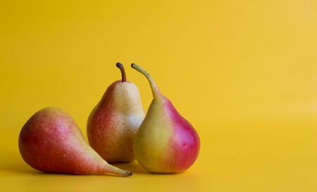 Three red yellow fresh pears isolated on  yellow background.の写真素材