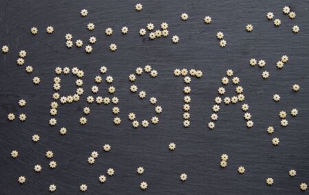 Pasta star shape isolated. Inscription PASTA on stone background. Top view.の写真素材