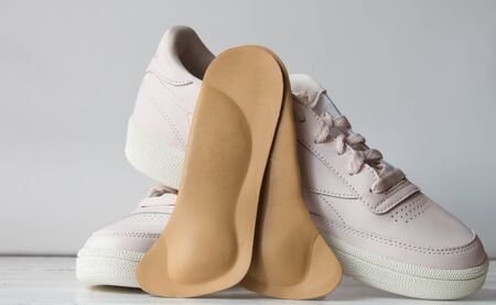 Orthopedic insoles with sports shoes isolated on white wooden board. Foot care conception.の写真素材