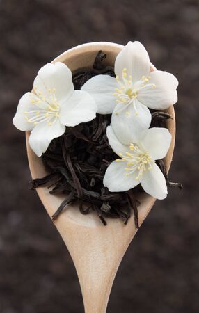 Wooden spoon with dry tea and jasmine flowers on tea background. Top view.の写真素材