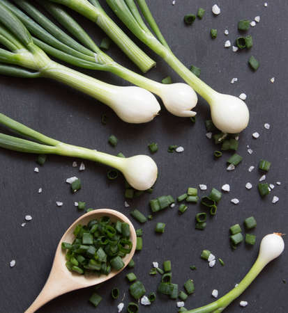 Pile of green onion and herb chopped in wooden spoon. Stone background. Top view.の写真素材