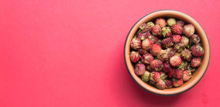 Fresh ripe red berries of wild forest strawberries in brown bowl. top view. red background. Summer menu, natural vitaminsの写真素材