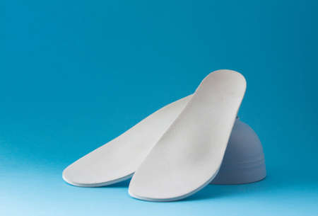 Leather orthopedic insoles on blue background. Prevention and treatment of flat feet. footcare.の写真素材